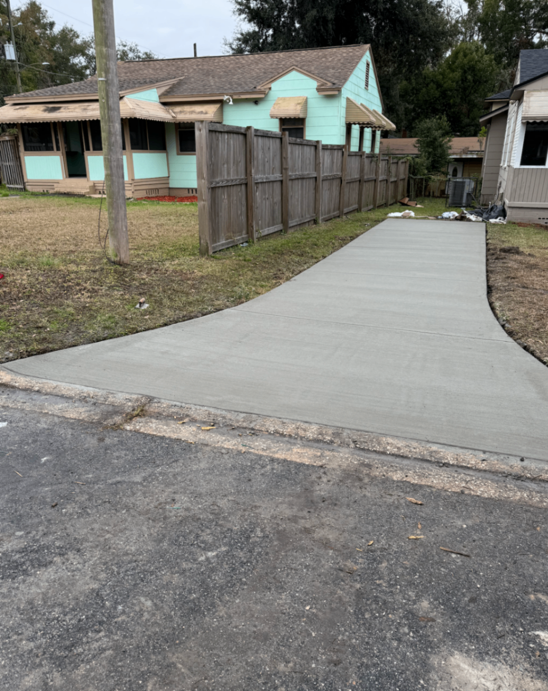 newly poured concrete driveway being broom-finished in front of a Columbus brick home